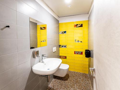 a bathroom with a sink and a yellow wall at Marathon Hostel in Genova