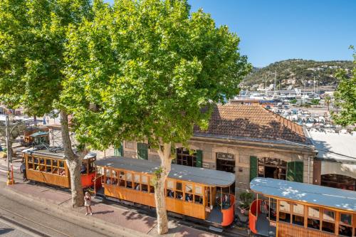 two trains parked at a train station with trees at Seafront Apartment in Port Sóller in Port de Soller