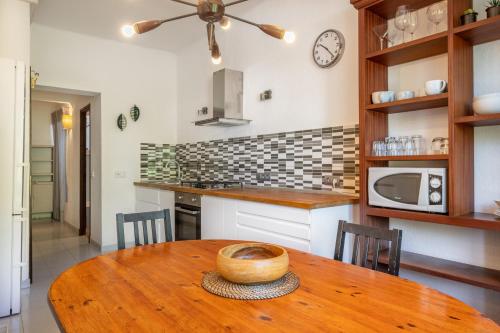 a kitchen with a wooden table and a clock on the wall at Seafront Apartment in Port Sóller in Port de Soller
