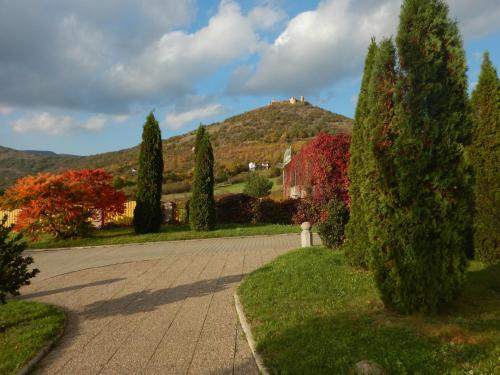a driveway with trees and a castle on a hill at Penzión Réva in Turna nad Bodvou