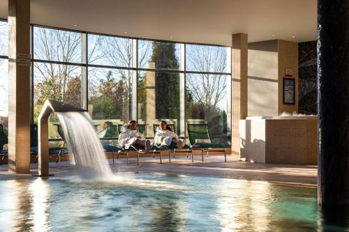 zwei Personen sitzen auf Stühlen in einem Pool mit Springbrunnen in der Unterkunft The Heritage in Killenard