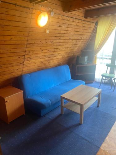 a blue couch and a coffee table in a room at Domki Topole in Białogóra