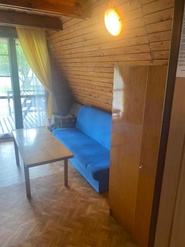 a blue couch in a room with a table at Domki Topole in Białogóra