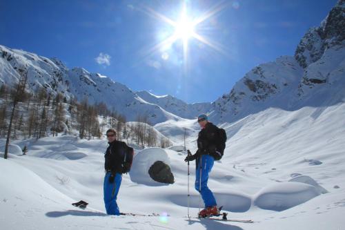 two men are standing in the snow on skis at Pension Oberhof in Sankt Lorenzen im Lesachtal