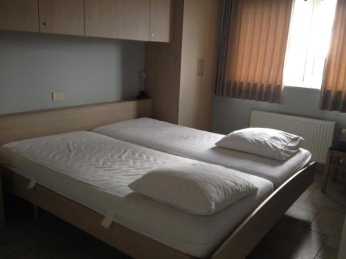 - un lit avec des draps et des oreillers blancs dans l'établissement Apartment Helena 4, à Blankenberge