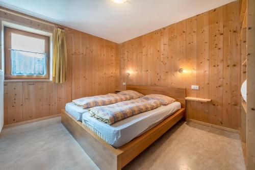 サン・ヴィジリオ・ディ・マレッベにあるCiasa La Palsa App 1の木製の壁のベッドルーム1室