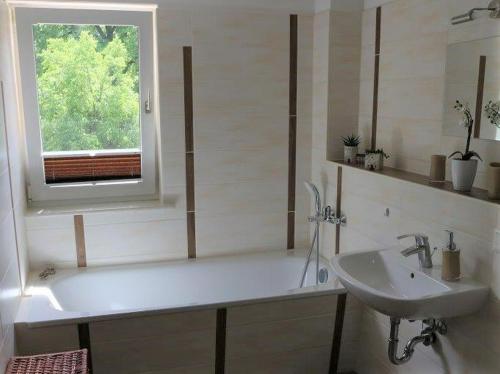 ein Bad mit einer Badewanne, einem Waschbecken und einem Fenster in der Unterkunft Ferienhaus Ochsenauge in Weimar