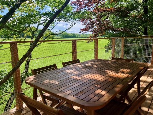 a wooden table and chairs on a deck with a fence at Cabanes de la Grande Noe in Les Épasses