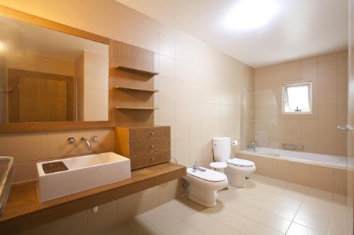 een badkamer met een wastafel, een toilet en een bad bij Arte da Fuga in Lajes do Pico