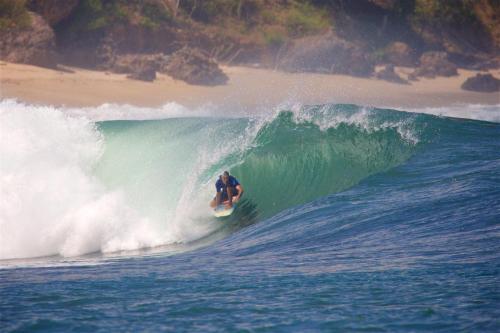 a man riding a wave on a surfboard in the ocean at Whales and Waves in Lemonga