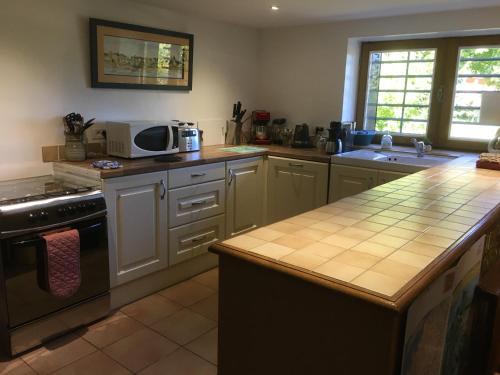 une cuisine avec des armoires blanches et un comptoir dans l'établissement La Garenne, à Exideuil