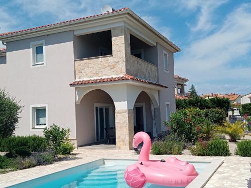 a pink swan in a swimming pool in front of a house at Villa Marie 5-Sterne in Kornić