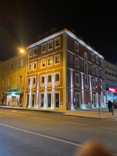 a yellow building on the side of a street at night at Maraveiro House in Aveiro