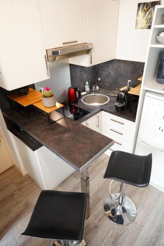 - une cuisine avec un comptoir et 2 chaises dans l'établissement Charmant studio au calme et bien desservi, à Paris