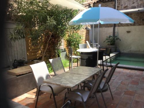uma mesa e cadeiras com um guarda-sol num pátio em Castel&Letti em Agde