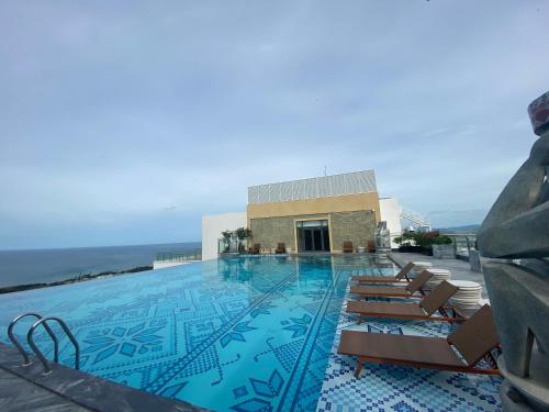 a swimming pool with chairs and the ocean in the background at IVORY Apartment Apec Phu Yen with POOL Access in Tuy Hoa