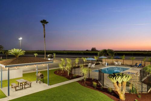 a view of a resort with a pool and picnic tables at Super 8 by Wyndham Lindsay Olive Tree in Lindsay
