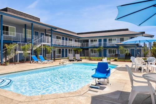 a swimming pool with chairs and tables and a building at Super 8 by Wyndham Lindsay Olive Tree in Lindsay