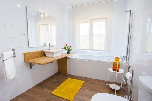 a white bathroom with a tub and a sink at Quinta do Vale Vendeiro in Figueira da Foz