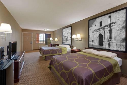 a hotel room with two beds and a flat screen tv at Super 8 by Wyndham San Antonio/Riverwalk Area in San Antonio