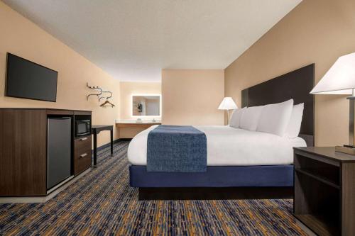 a hotel room with a bed and a flat screen tv at Super 8 by Wyndham Lindsay Olive Tree in Lindsay
