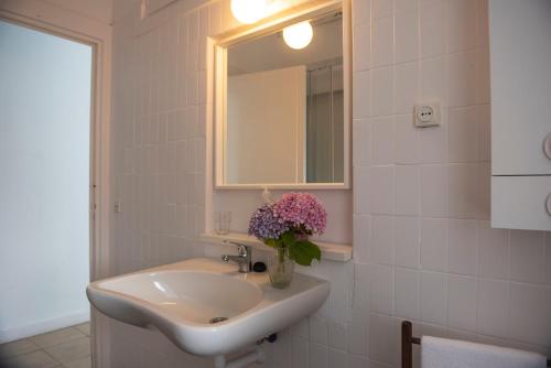 bagno con lavandino, specchio e fiori di Chalet en El Sardinero a 5 minutos de la playa. a Santander