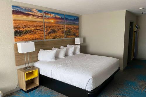 a hotel room with a bed with two paintings on the wall at Days Inn by Wyndham Waco University Area in Waco