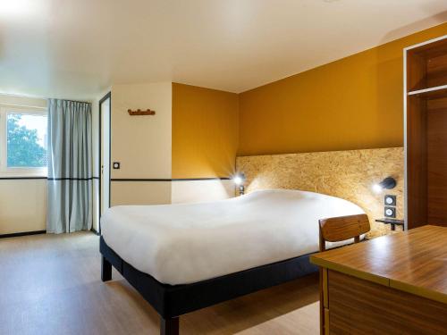 een hotelkamer met een groot bed en een bureau bij Greet Hôtel Villeneuve la Garenne - rénové in Villeneuve-la-Garenne