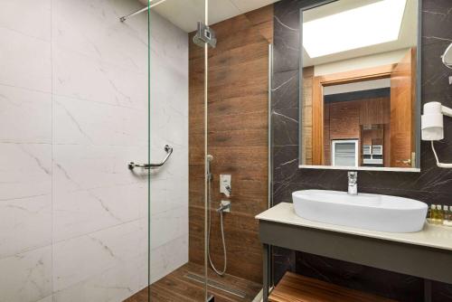 a bathroom with a sink and a glass shower at Ramada Plaza by Wyndham Samsun in Samsun
