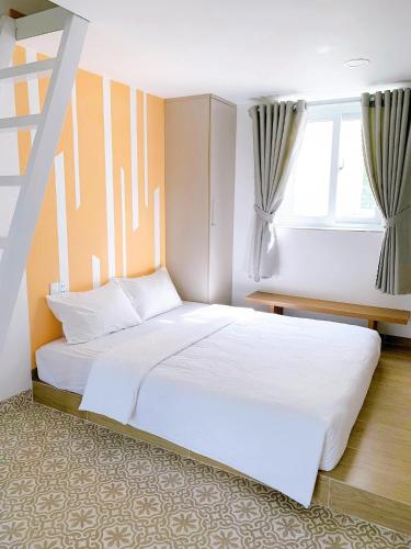 a bedroom with a large white bed and two windows at Lá Homestay in Mỹ Phước