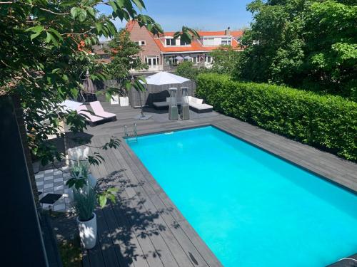 a large blue swimming pool next to a garden at Finch guesthouse in Zandvoort