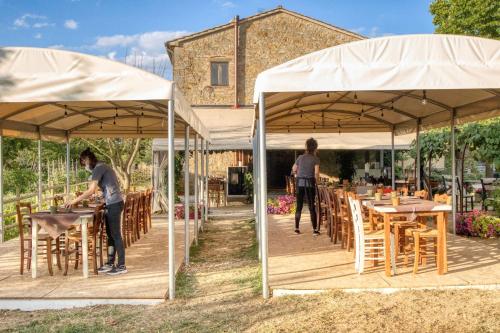 two men standing under umbrellas with tables and chairs at La Casa Di Campagna in Magione