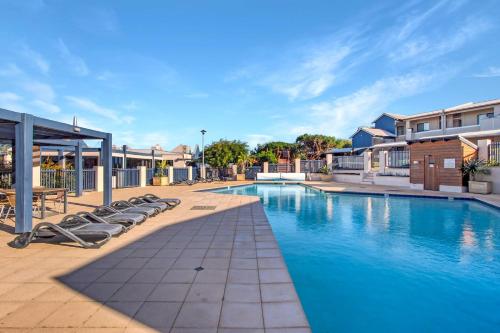 a swimming pool with lounge chairs next to a building at A Stones Throw Gnarabup in Gnarabup