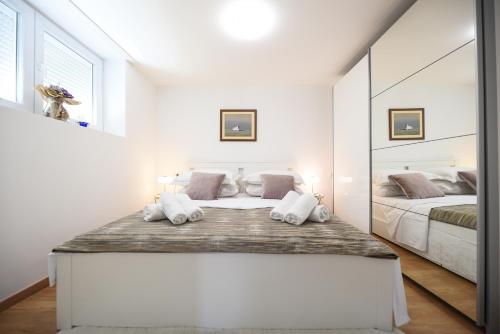 Habitación blanca con cama y espejo en Apartman Maja, en Zadar