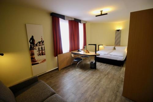 a hotel room with a bed and a table and a couch at TRYP by Wyndham Halle in Halle an der Saale