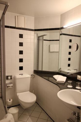 a bathroom with a toilet and a sink at TRYP by Wyndham Halle in Halle an der Saale