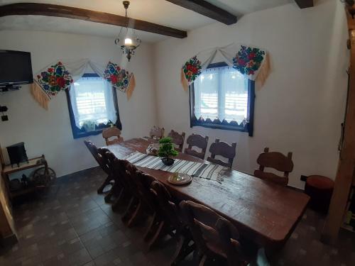 a dining room with a long wooden table and chairs at Căsuța din Povești - Vatra in Vatra Dornei