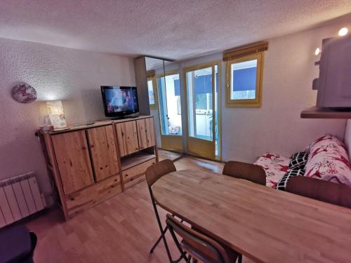 a living room with a wooden table and a television at La Foux d'Allos - Studio 4 couchages, très proche centre station in La Foux