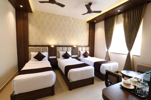 a hotel room with two beds and a table at Mayuraa Residency in Chennai