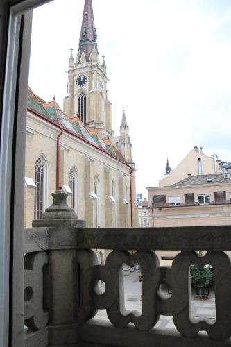a view of a church with a clock tower from a window at Apartment Centrum in Novi Sad