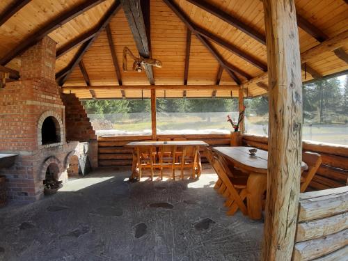 einem großen Holzpavillon mit einem Tisch und einem Kamin in der Unterkunft Căsuța din Povești - Vatra in Vatra Dornei