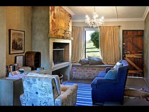 a living room with a couch and chairs and a fireplace at Courchevel Cottages in Franschhoek