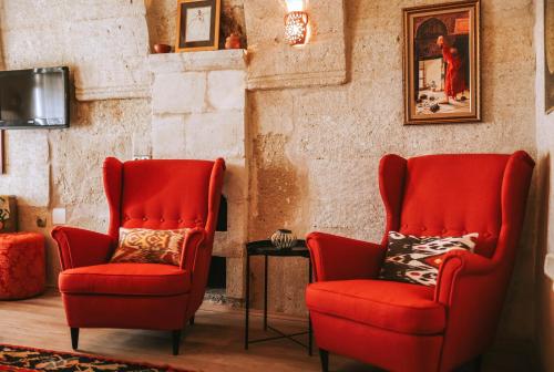 two red chairs in a living room with a table at Elaa Cave Hotel in Ortahisar
