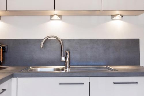 a kitchen with a sink and white cabinets at Living Lerchna - Apartment Abendrot in Maranza