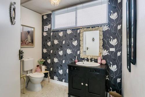 a bathroom with a sink and a toilet and a mirror at 'Ooh La La' is a quirky French inspired apartment in Goolwa South