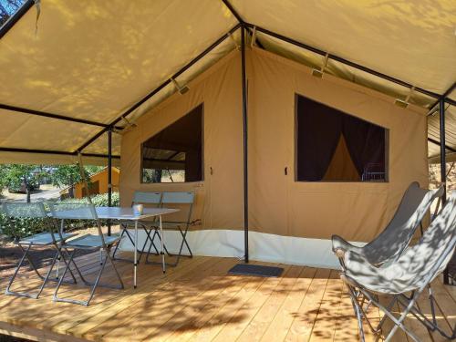 uma tenda com uma mesa e cadeiras num deque de madeira em Camping ONLYCAMP LES PINS em Nançay