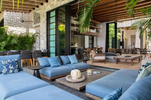 a living room with blue couches and a patio at Clay Beach Samui in Nathon Bay