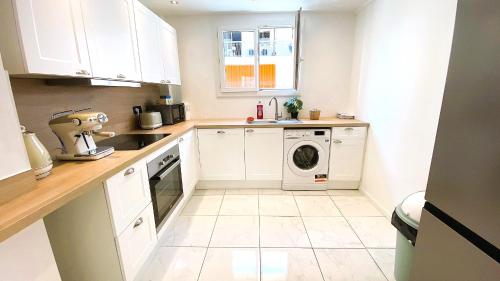 une cuisine avec des armoires blanches et une laveuse et une sécheuse dans l'établissement Marie Antoinette - Appartement 2 Chambres, centre ville, terrasse, moderne, à Antibes
