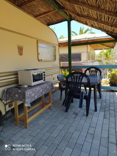 eine Terrasse mit einem Tisch und Stühlen sowie einem Wohnwagen in der Unterkunft camping hydraswave bungalow caravan in Thermisía