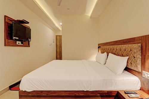a bedroom with a white bed with a flat screen tv at Hotel Heera Grand in Lucknow